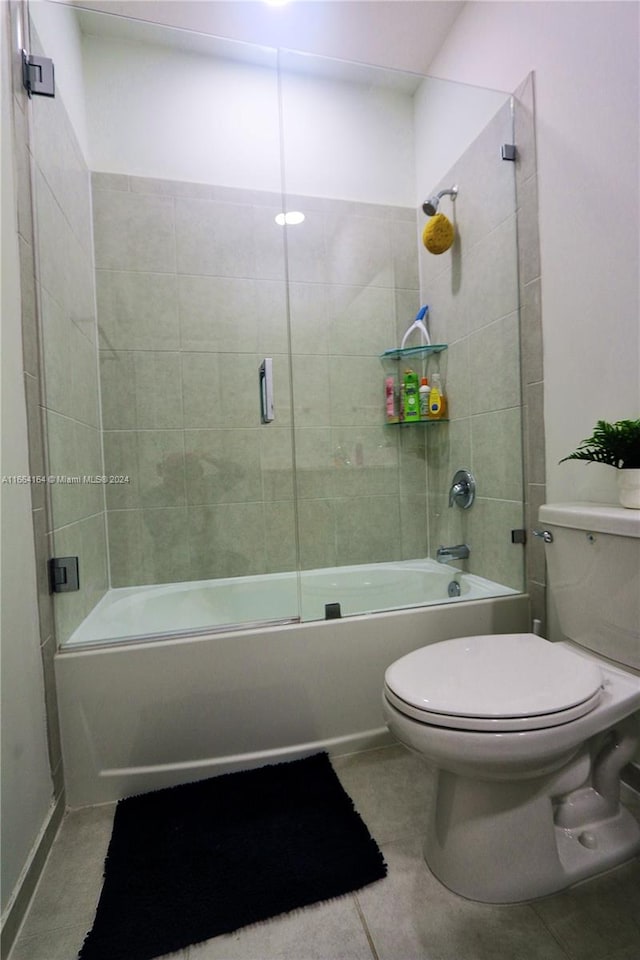 bathroom with combined bath / shower with glass door, toilet, and tile patterned floors