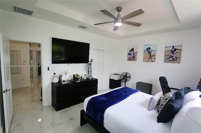 bedroom with ceiling fan, a tray ceiling, and a closet