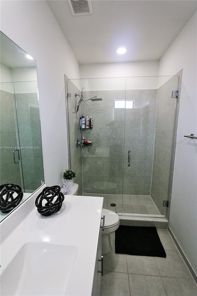 bathroom with vanity, a shower with shower door, toilet, and tile patterned floors