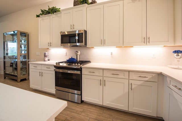 kitchen with backsplash, appliances with stainless steel finishes, light wood-type flooring, and white cabinetry