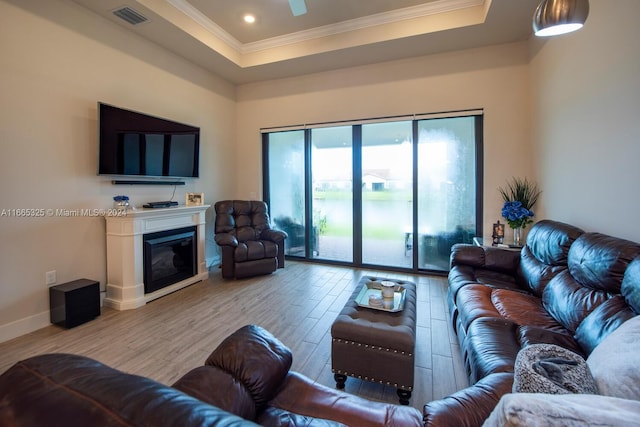 living room featuring ornamental molding, a tray ceiling, and light hardwood / wood-style flooring