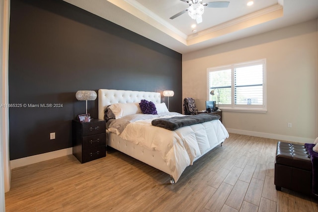 bedroom with wood-type flooring, crown molding, a tray ceiling, and ceiling fan