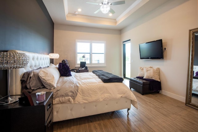 bedroom with crown molding, ceiling fan, a tray ceiling, and hardwood / wood-style floors