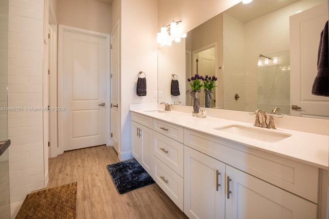 bathroom with wood-type flooring, vanity, and tiled shower