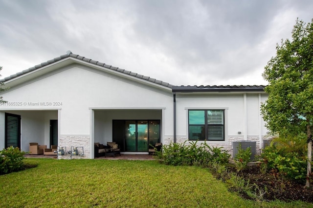 rear view of property featuring a yard, a patio area, and central AC