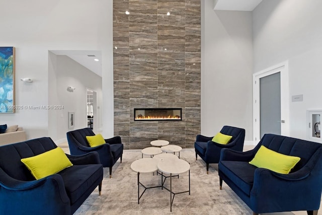 living room with tile walls, a high ceiling, and a tile fireplace