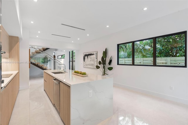 kitchen featuring a large island, light stone counters, dishwasher, sink, and light brown cabinets