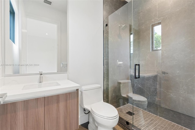 bathroom featuring a shower with shower door, vanity, and toilet