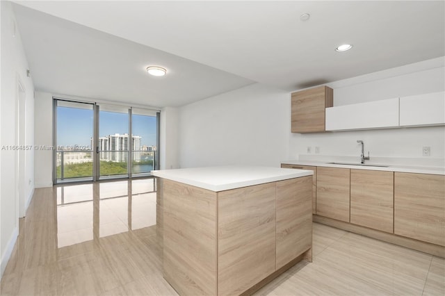 kitchen with light brown cabinetry, floor to ceiling windows, light countertops, modern cabinets, and a sink