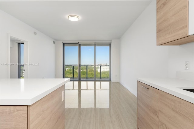 kitchen with light brown cabinetry, floor to ceiling windows, modern cabinets, and light countertops