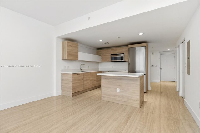 kitchen featuring sink, black appliances, light brown cabinets, and light wood-type flooring