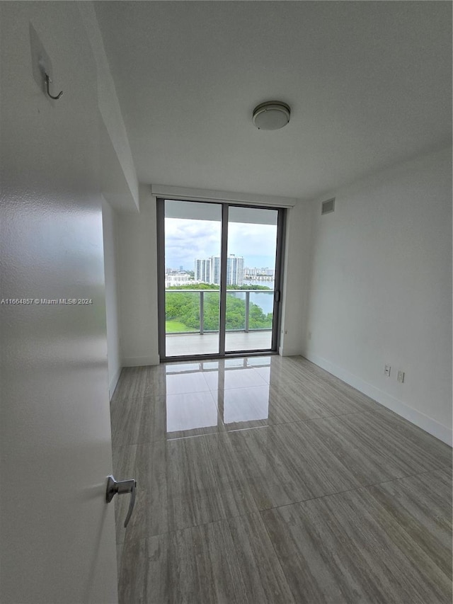 unfurnished room with hardwood / wood-style floors and expansive windows