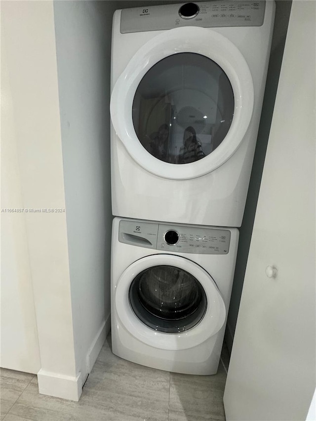 laundry room with light tile patterned floors and stacked washer and clothes dryer