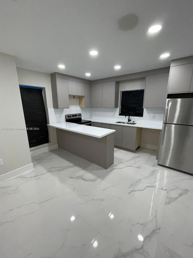 kitchen featuring appliances with stainless steel finishes, sink, kitchen peninsula, gray cabinets, and a breakfast bar