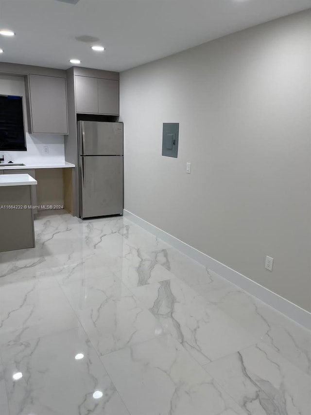 kitchen with built in desk, stainless steel refrigerator, sink, and gray cabinets