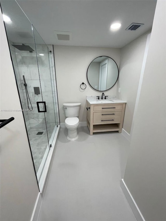 bathroom with a shower with door, vanity, toilet, and tile patterned floors