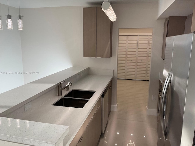 kitchen featuring light tile patterned floors, decorative light fixtures, stainless steel fridge, and sink