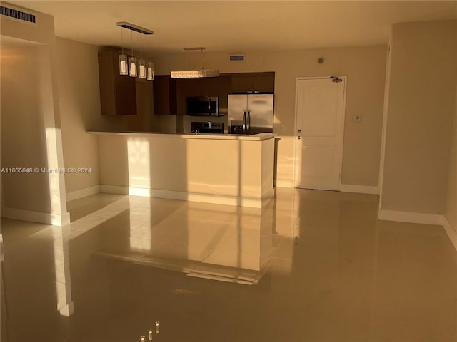 kitchen featuring light tile patterned floors, appliances with stainless steel finishes, hanging light fixtures, and dark brown cabinetry