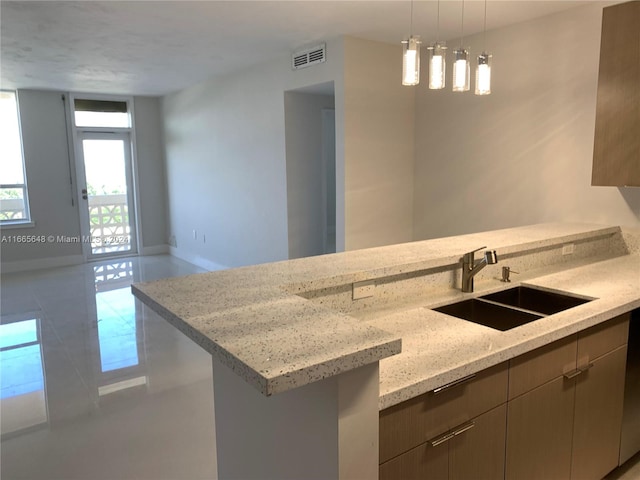 kitchen with light stone countertops, sink, and pendant lighting