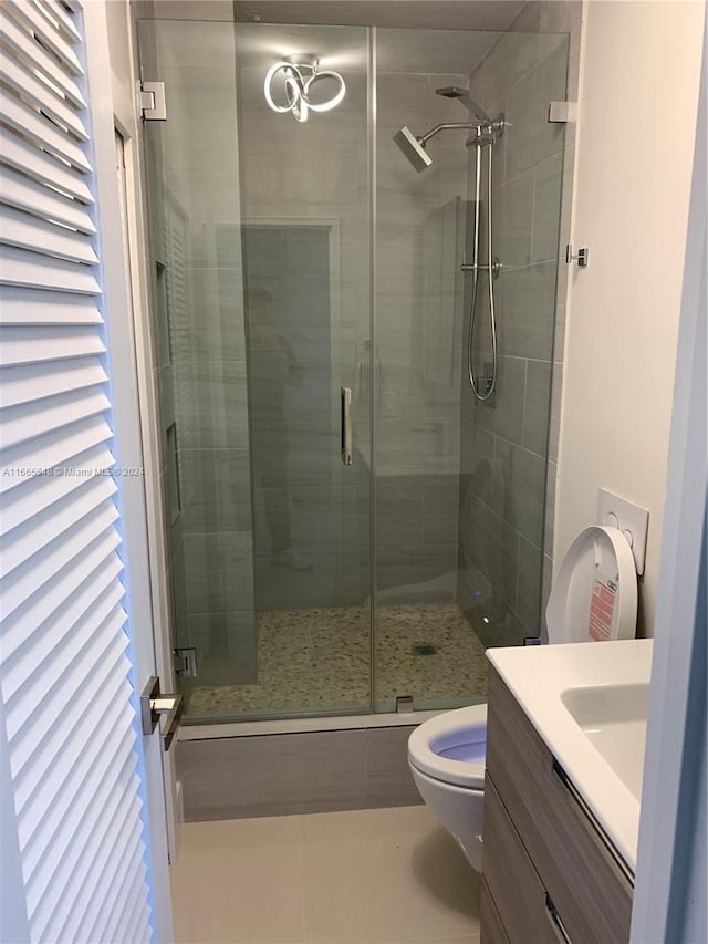 bathroom with vanity, toilet, tile patterned floors, and a shower with shower door