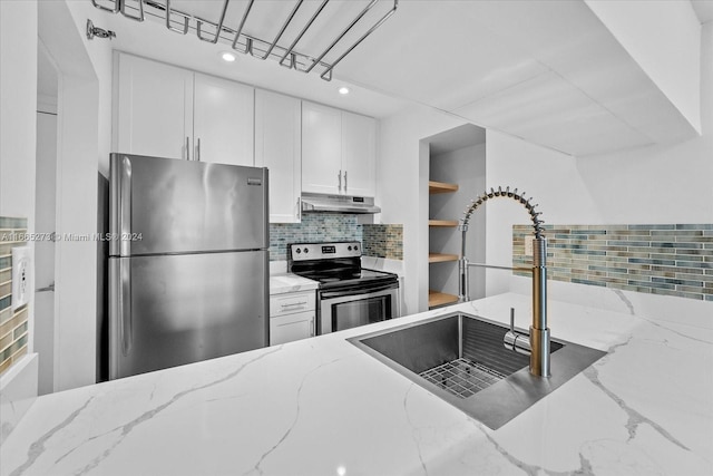 kitchen with light stone countertops, stainless steel appliances, and white cabinetry