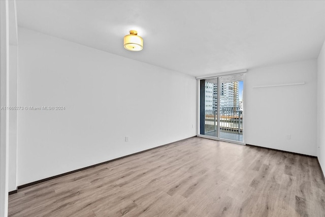 spare room featuring light wood-type flooring and a wall of windows