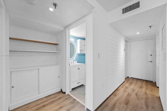 corridor featuring wooden walls and light hardwood / wood-style flooring