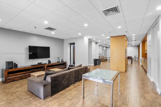 living room with light hardwood / wood-style floors and a paneled ceiling