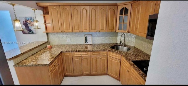 kitchen with sink, tasteful backsplash, dark stone counters, hanging light fixtures, and black electric stovetop