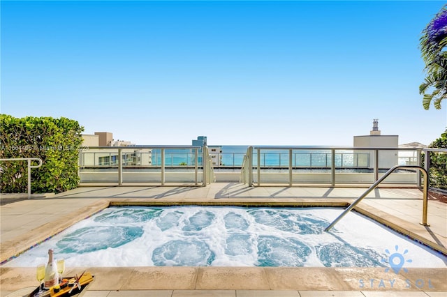 view of pool with an in ground hot tub and a water view