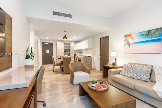 living area with visible vents, light wood-style flooring, and recessed lighting