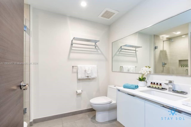 bathroom featuring vanity, toilet, a shower with door, and tile patterned floors