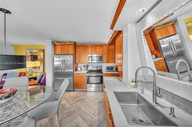 kitchen featuring appliances with stainless steel finishes, tasteful backsplash, pendant lighting, light parquet floors, and sink