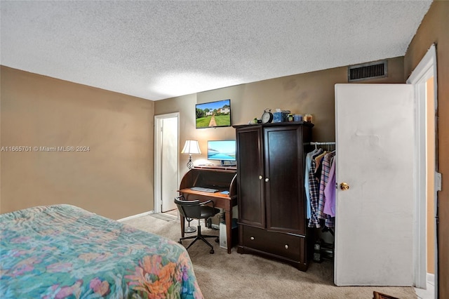 bedroom with a textured ceiling and light colored carpet