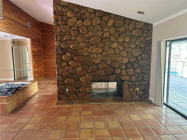 unfurnished living room featuring light tile patterned flooring, crown molding, a fireplace, and wooden walls