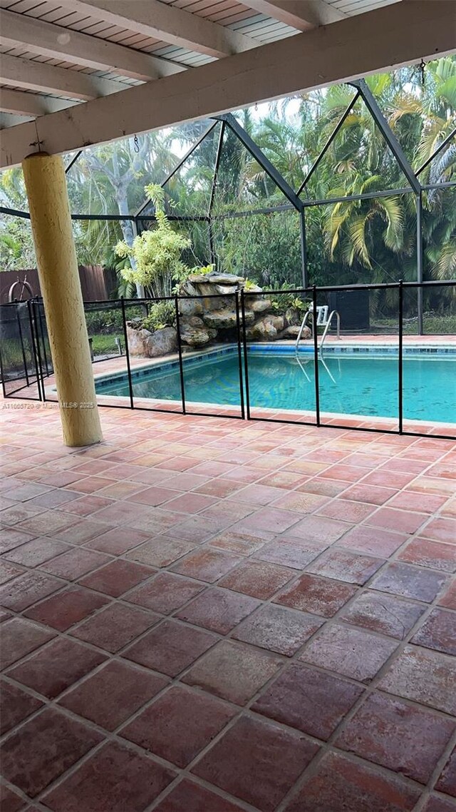 view of swimming pool with ceiling fan and glass enclosure