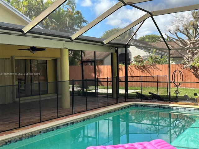 view of swimming pool with a patio area, ceiling fan, and glass enclosure