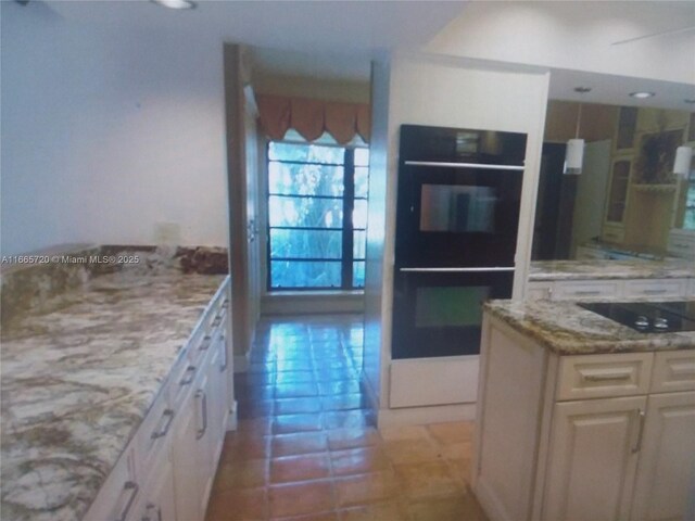 kitchen featuring pendant lighting, light tile patterned floors, light stone countertops, black appliances, and a kitchen island