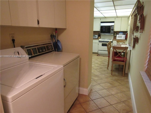 laundry area with washing machine and clothes dryer, cabinets, and light tile patterned floors