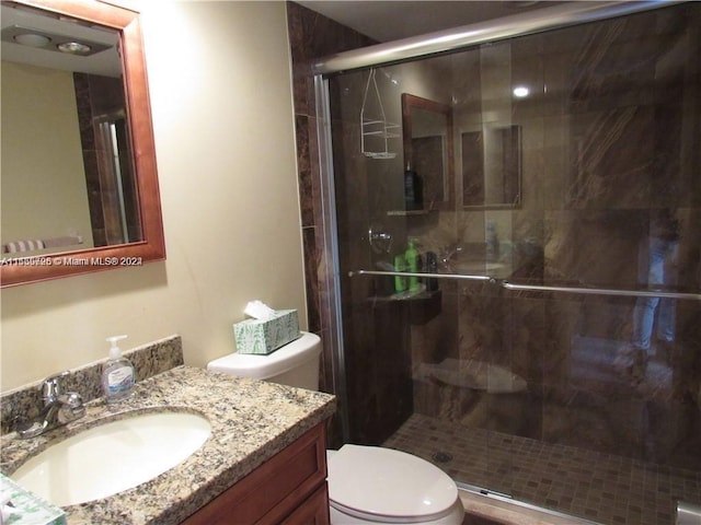 bathroom with vanity, toilet, and a shower with door