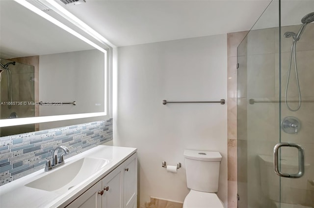 bathroom featuring backsplash, a shower with door, vanity, and toilet