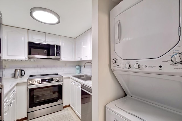 laundry area with light wood-type flooring, stacked washer / dryer, and sink