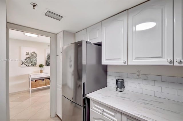 1621 Bay Rd Unit 1105, Miami Beach, FL 33139 - kitchen featuring freestanding refrigerator, light tile patterned floors, light stone counters, visible vents, and white cabinets