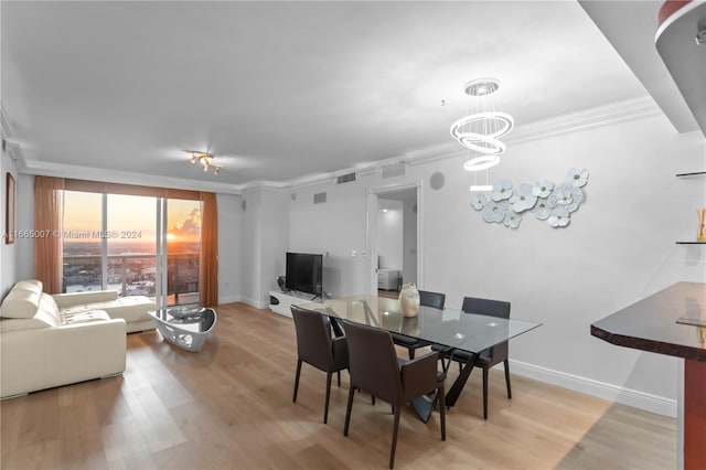 dining room featuring an inviting chandelier, light hardwood / wood-style flooring, and crown molding