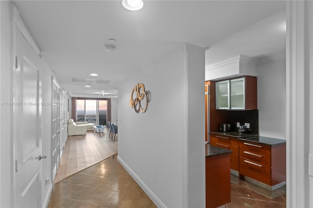 hallway featuring dark tile patterned flooring and crown molding