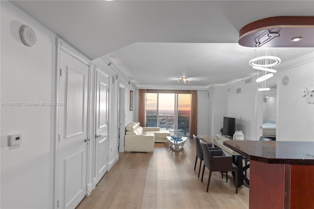 dining area with light hardwood / wood-style flooring, a notable chandelier, and crown molding