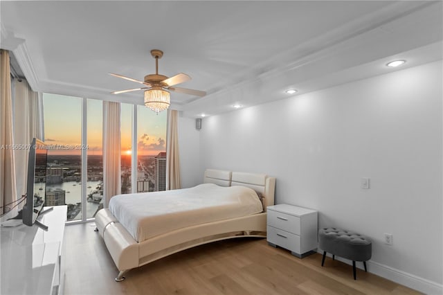 bedroom featuring light wood-type flooring, floor to ceiling windows, ceiling fan, and access to exterior