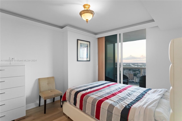 bedroom with hardwood / wood-style flooring, access to outside, and crown molding