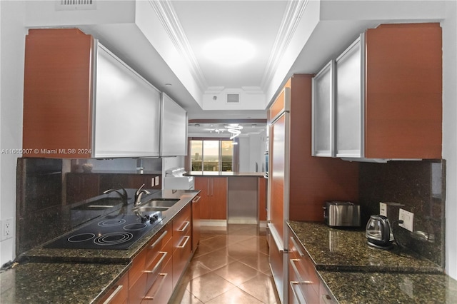 kitchen with sink, dark stone counters, ornamental molding, and tasteful backsplash