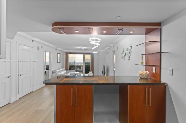 kitchen with dark stone countertops, light hardwood / wood-style flooring, and ornamental molding